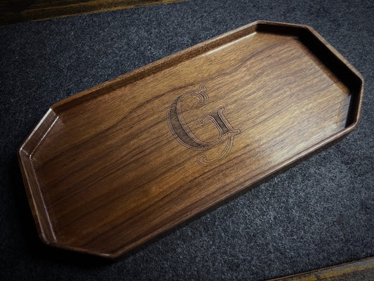 Lonoke Designs walnut hardwood catchall tray with a custom engraved letter 'G' sitting on a gray wool desk pad.