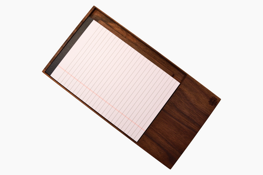 A walnut notepad holder with a notepad and a pen resting on top of it, isolated on a white background.