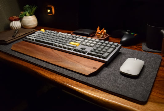 A desk pad made of wool felt and cork, displayed on a desk with a keyboard and mouse on top.