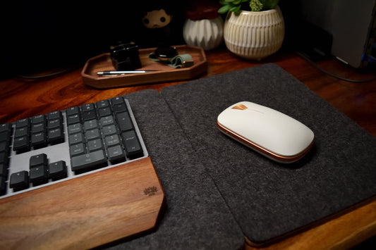 Charcoal mouse pad and desk pad combined on wood desk with mouse and keyboard.