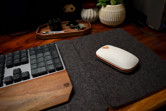 Charcoal mouse pad and desk pad combined on wood desk with mouse and keyboard.