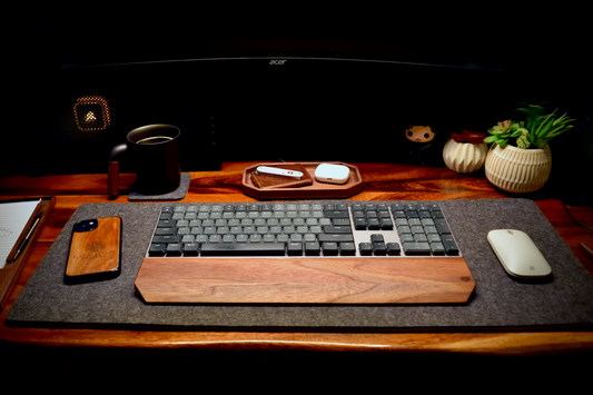 Lonoke Designs desk setup with walnut wrist rest, keyboard, walnut iphone on a grey wool desk pad.