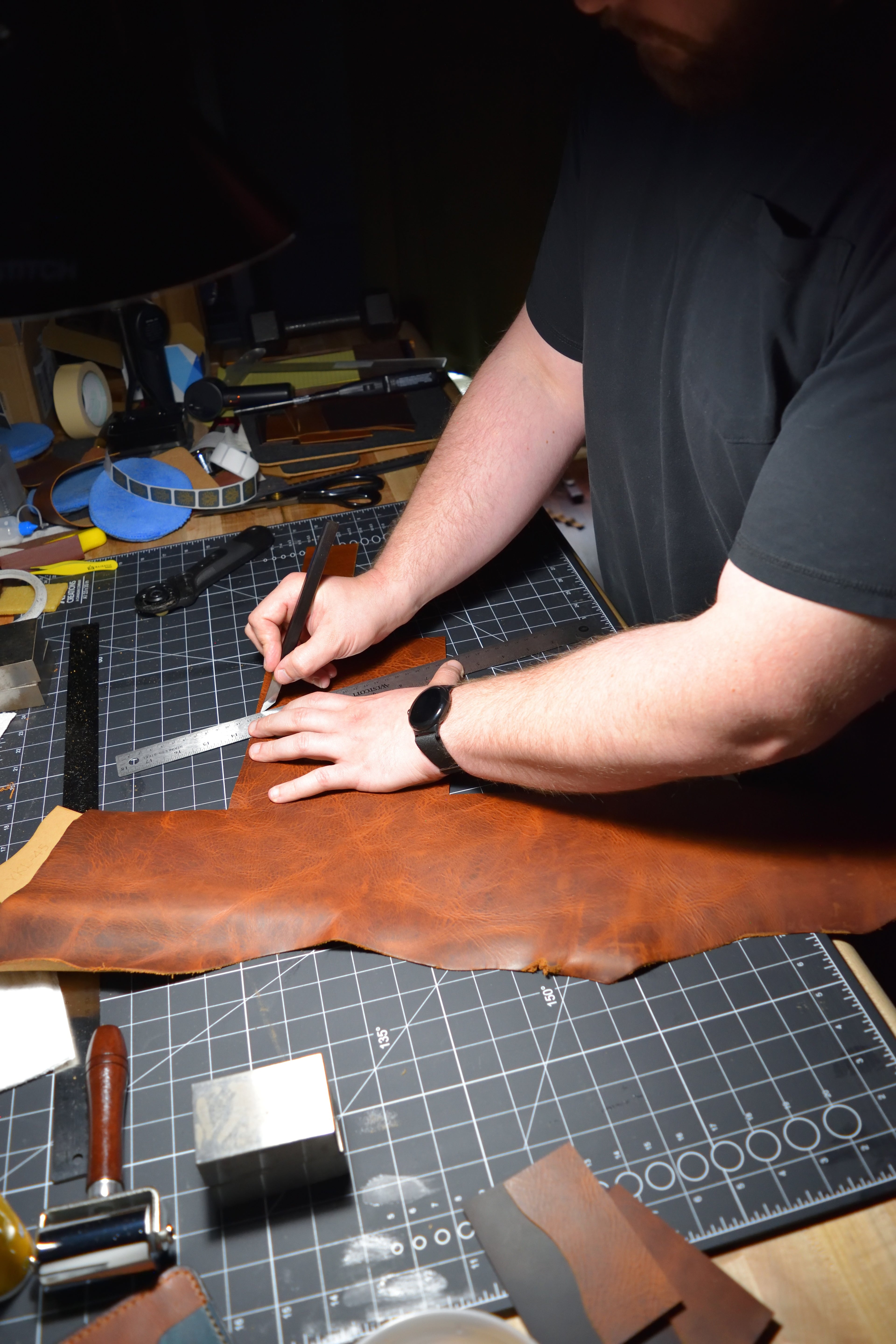 Person working with leather on a cutting mat in the Lonoke Designs workshop.