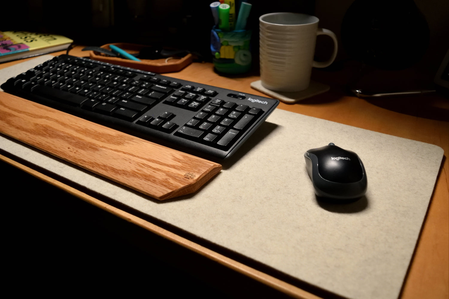 Keyboard and mouse on a Lonoke Designs wool white Lonoke Designs desk pad with a mug and stationery items.