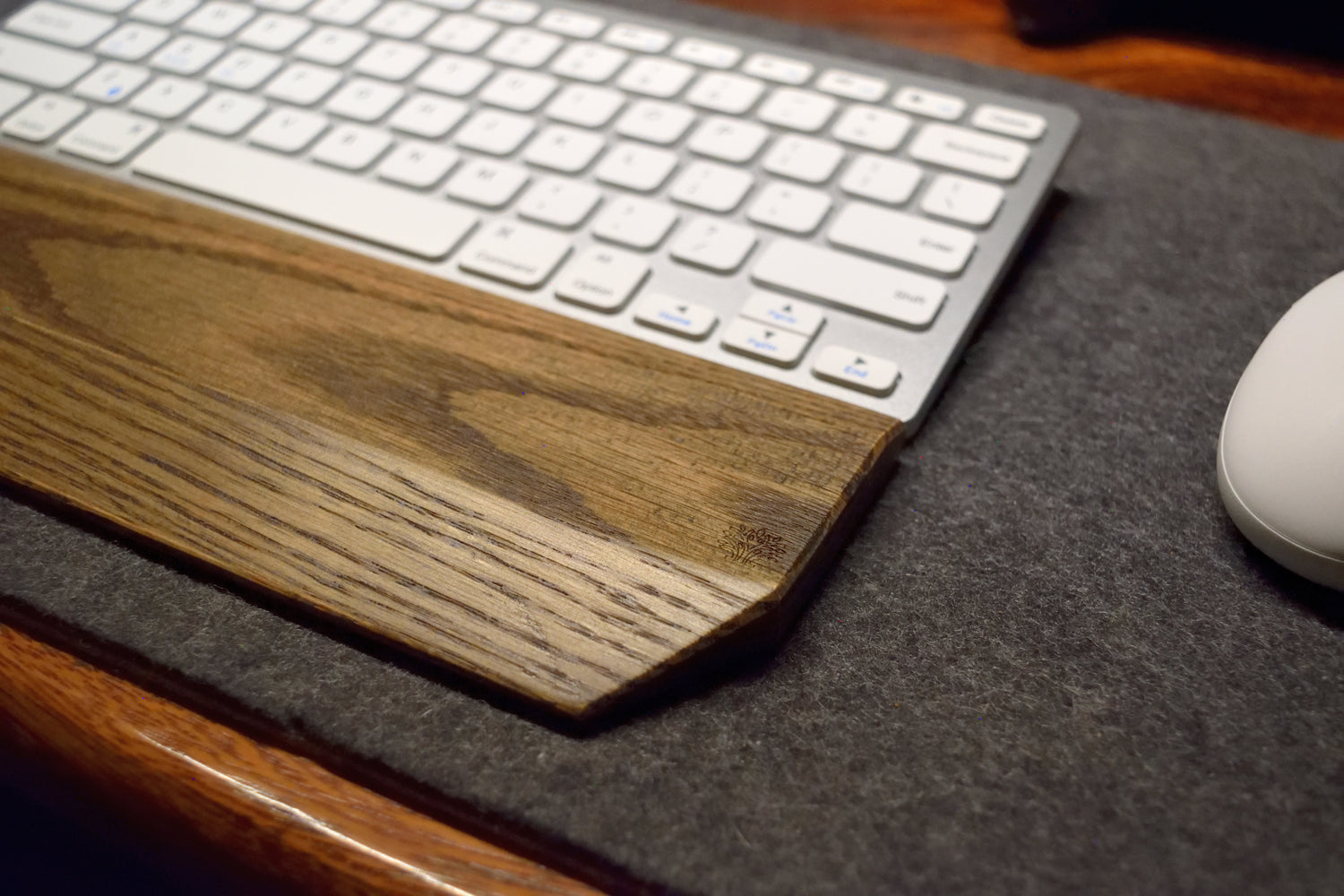 Black-stained oak keyboard wrist rest with a keyboard and mouse on a Lonoke Designs gray wool desk pad.
