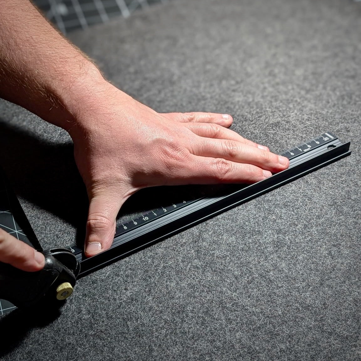 Hand cutting a Lonoke Designs wool desk pad with a black metal ruler.