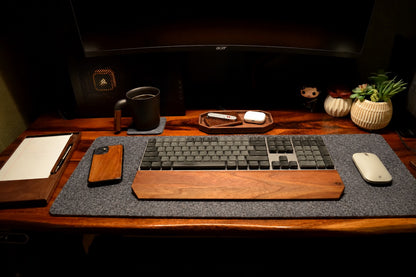 Wooden desk setup with keyboard, mouse, phone, and mug on a dark background