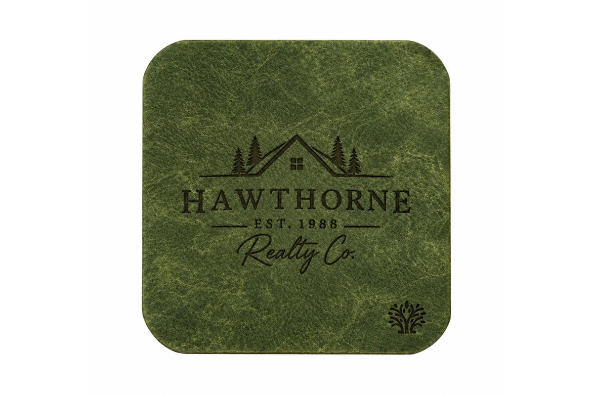 An Emerald green veg-tanned leather square coaster with rounded corners, featuring a small Lonoke Designs logo in the bottom right corner, set against a plain white background. Featuring an example of a company's custom laser engraving.