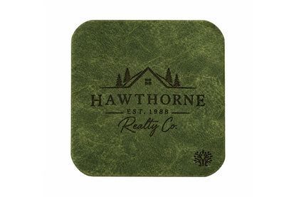 An Emerald green veg-tanned leather square coaster with rounded corners, featuring a small Lonoke Designs logo in the bottom right corner, set against a plain white background. Featuring an example of a company's custom laser engraving.