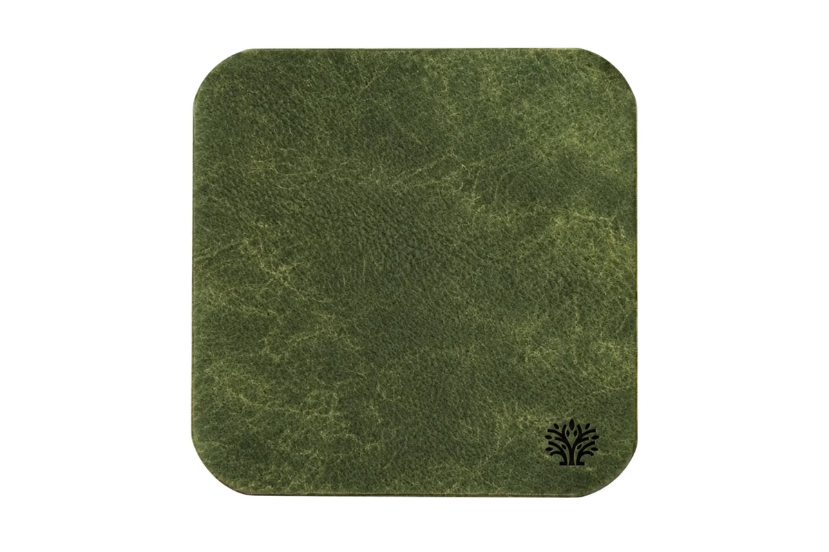 An Emerald green veg-tanned leather square coaster with rounded corners, featuring a small Lonoke Designs logo in the bottom right corner, set against a plain white background.