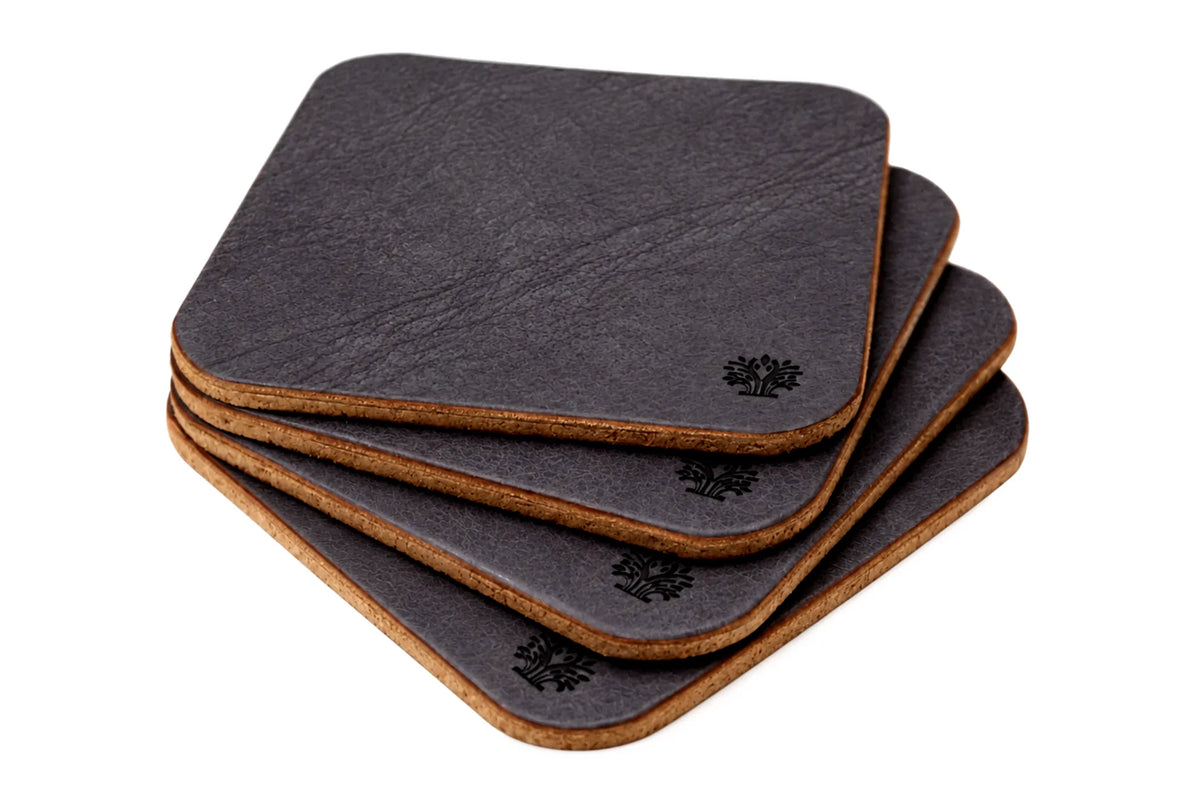A stack of four square coasters with rounded corners, featuring an Espresso dark brown vegetable-tanned leather top surface and a natural cork bottom, with a small Lonoke Designs logo printed on the corner.