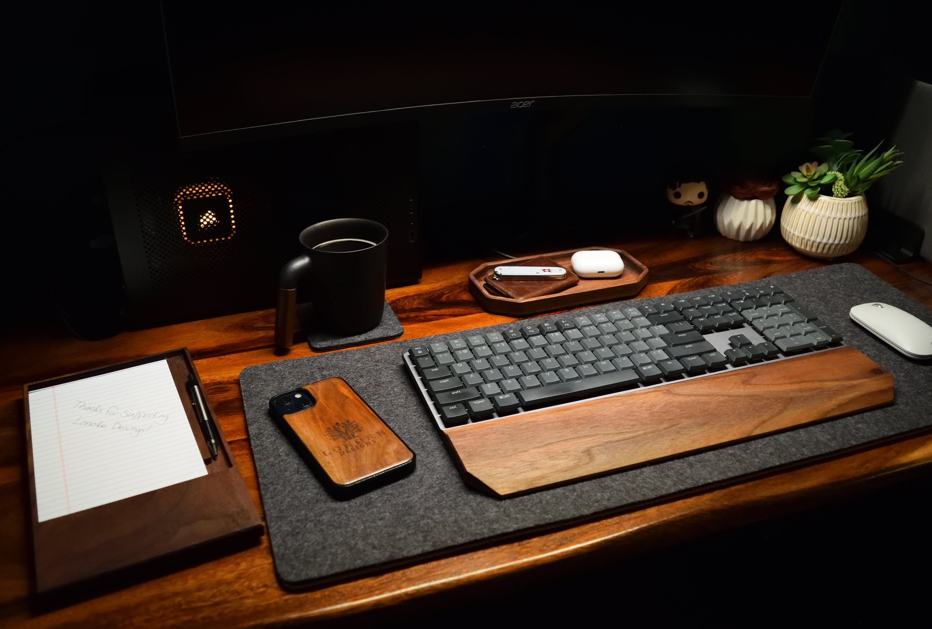 Full Lonoke Designs desk setup with a walnut notepad holder, mechanical keyboard wrist rest, catchall organizer tray, gray wool desk pad, and coaster.