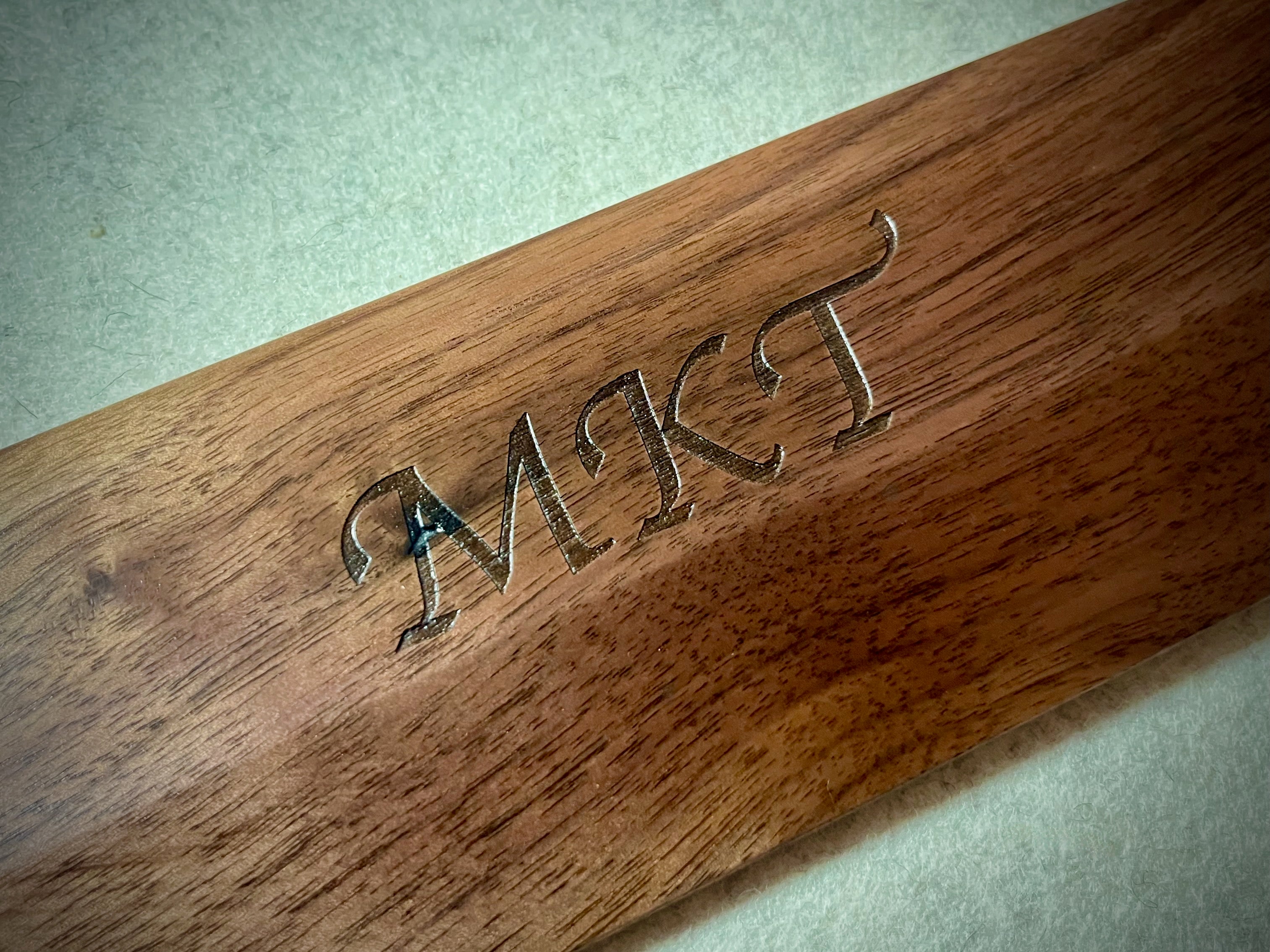 Lonoke Designs walnut wrist rest custom laser engraved with "MKT" in the center. Made in Texas.