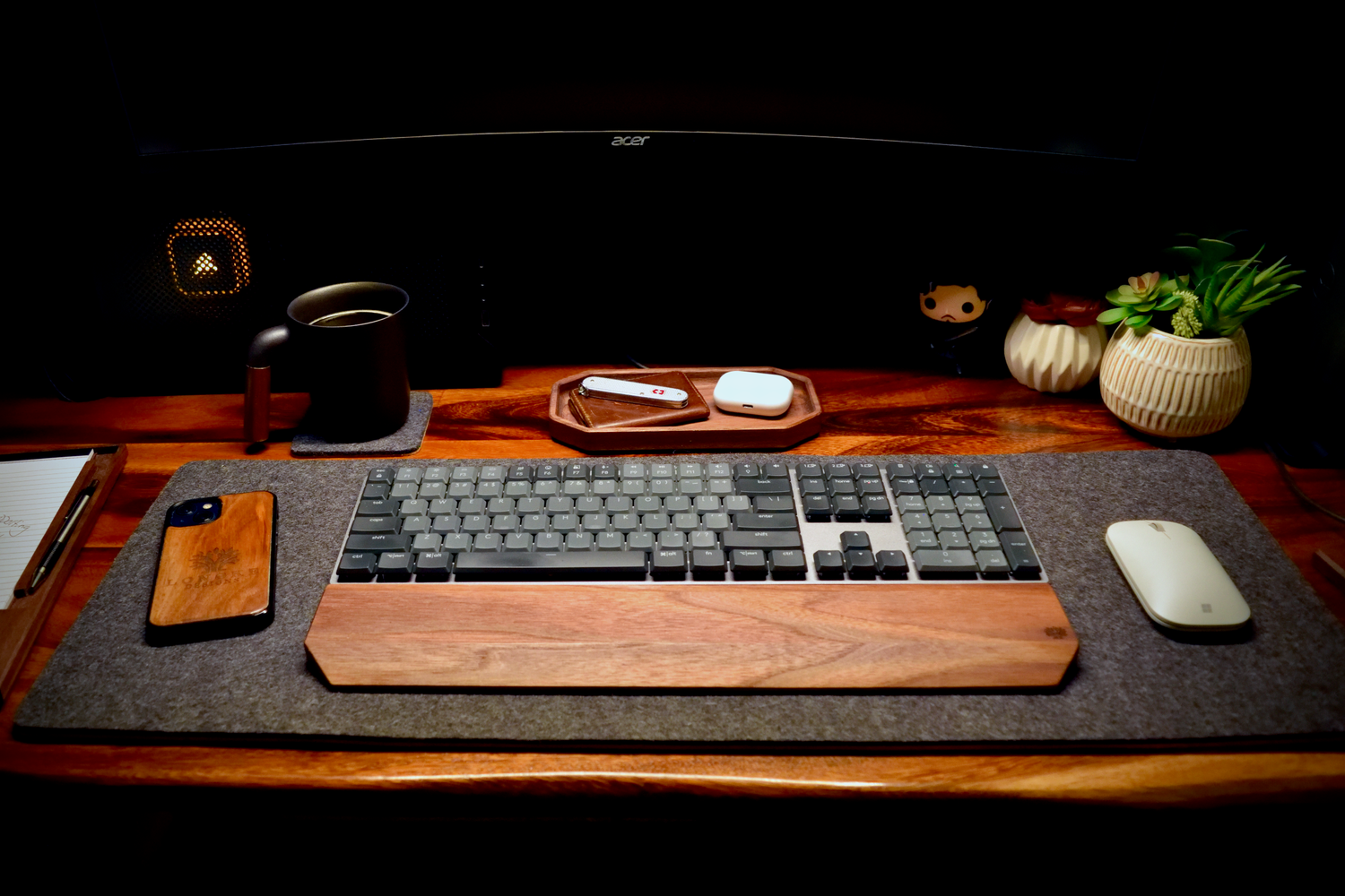 Wooden desk setup with keyboard, mouse, phone, and decor items.