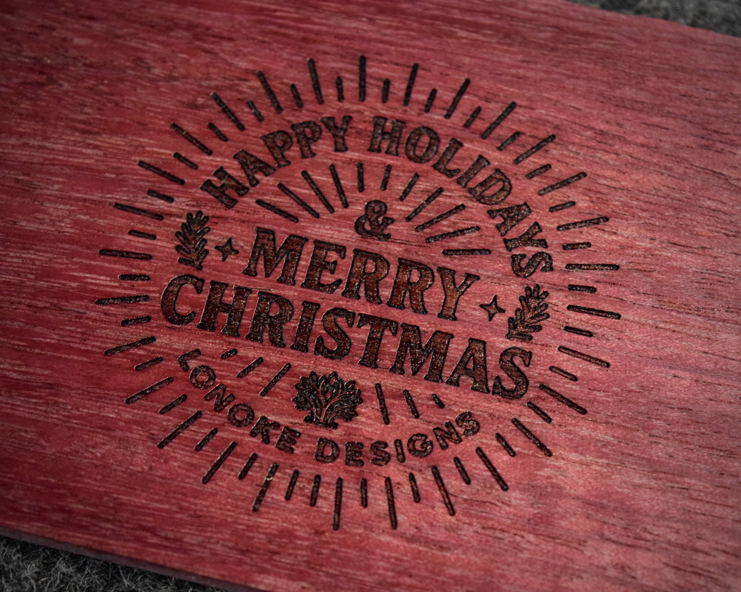 Wooden surface with 'Happy Holidays & Merry Christmas' engraving, Lonoke Designs.