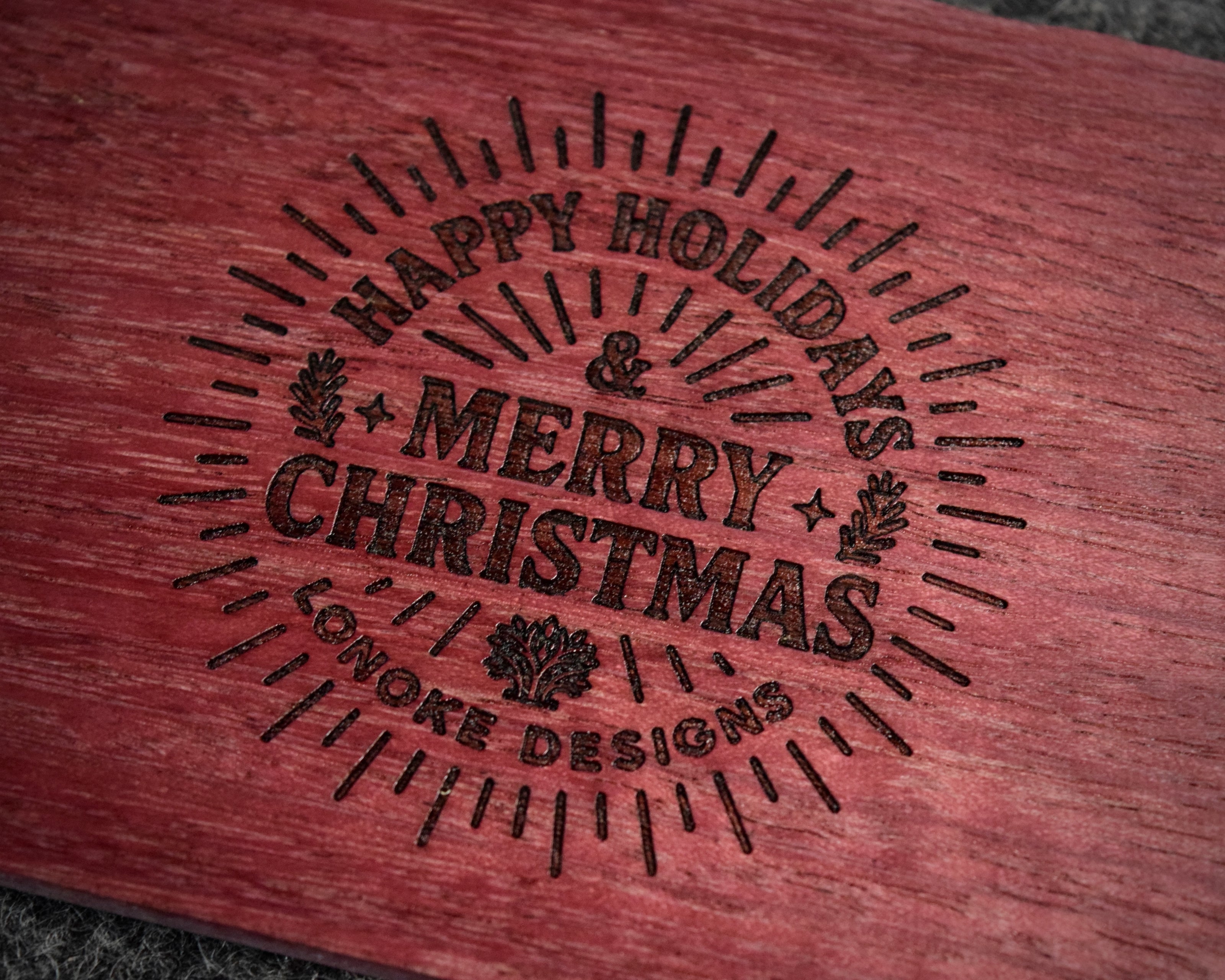 Wooden surface with 'Happy Holidays & Merry Christmas' engraving, Lonoke Designs.