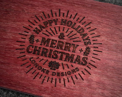 Wooden surface with 'Happy Holidays & Merry Christmas' engraving, Lonoke Designs.