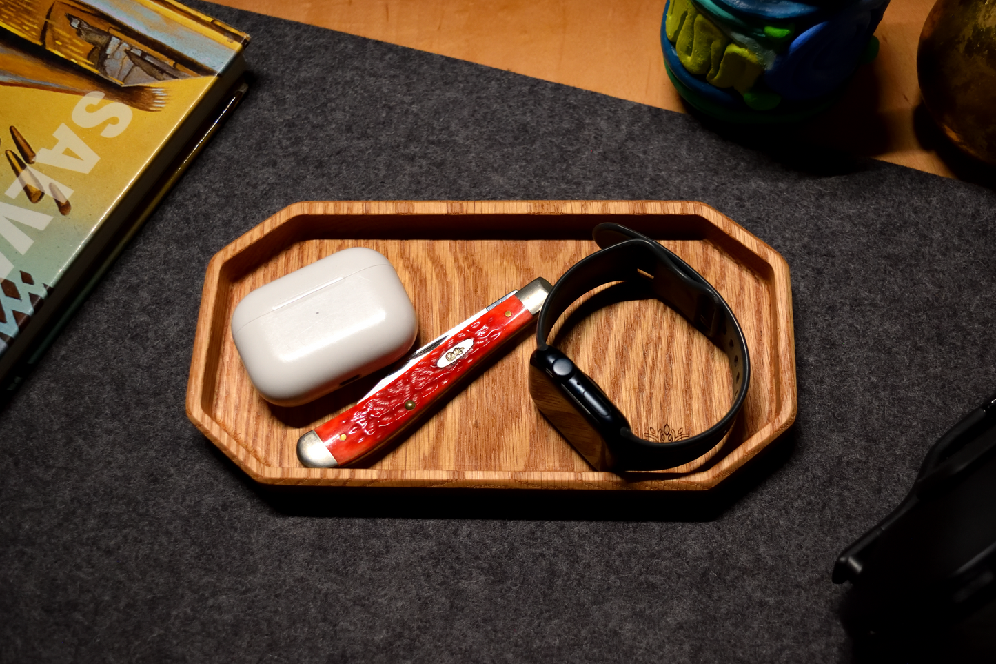 Wooden tray with Apple Air Pods, red Case pocket tool, and black Apple Watch in a oak organizer tray.