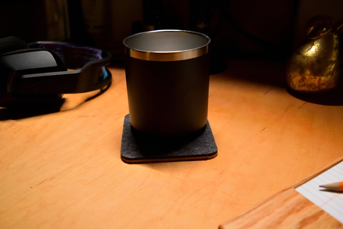 Shadow Gray wool coaster with a stainless steel mug, sitting on a wooden desk.