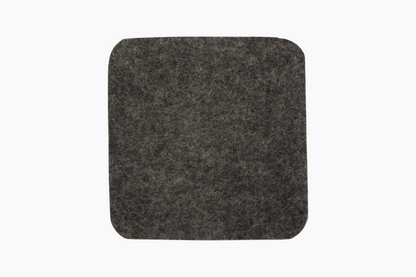 Square Shadow gray wool felt coasters with cork backing placed on a white surface.
