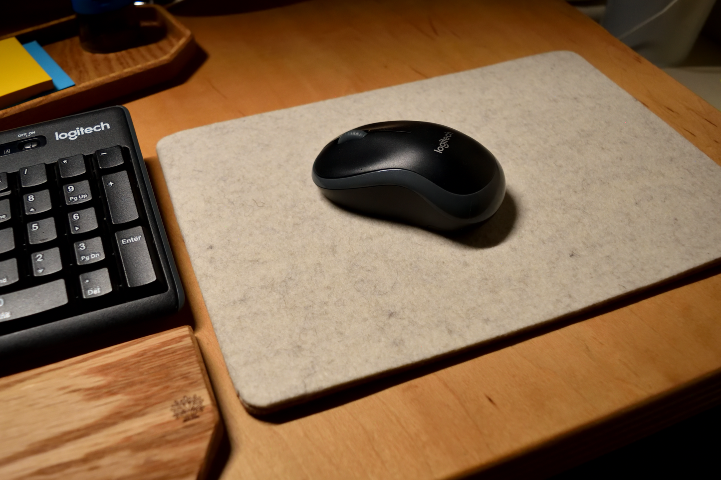 Logitech mouse and keyboard on a desk with a wool mouse pad