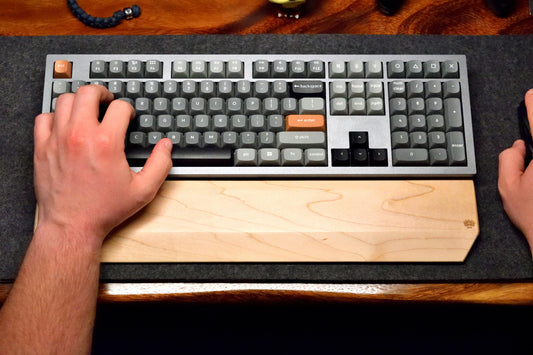 A person typing on a mechanical keyboard with a Lonoke Designs Maple Hardwood keyboard wrist rest.