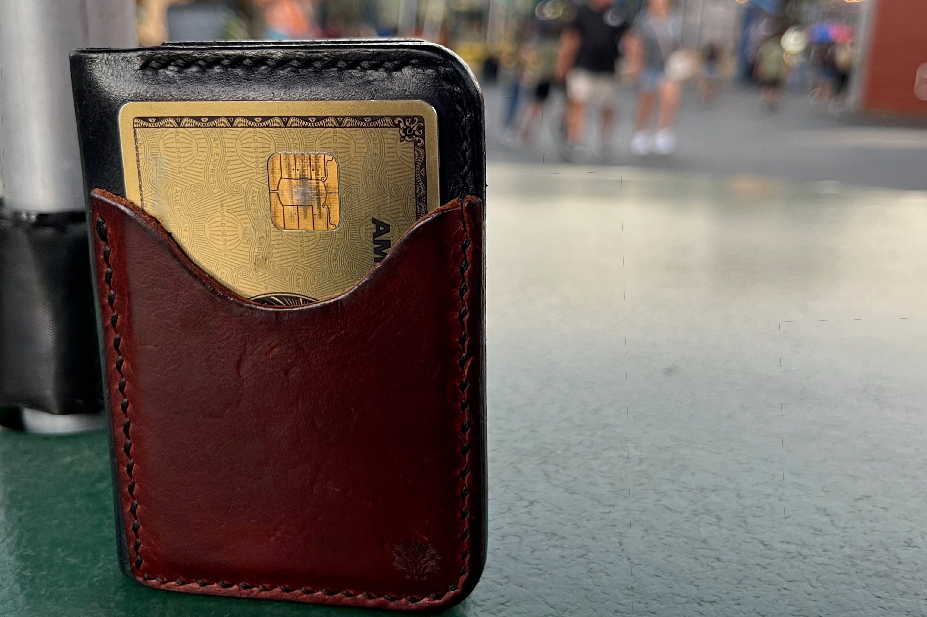 Brown leather wallet with a gold card on a blurred amusement park background