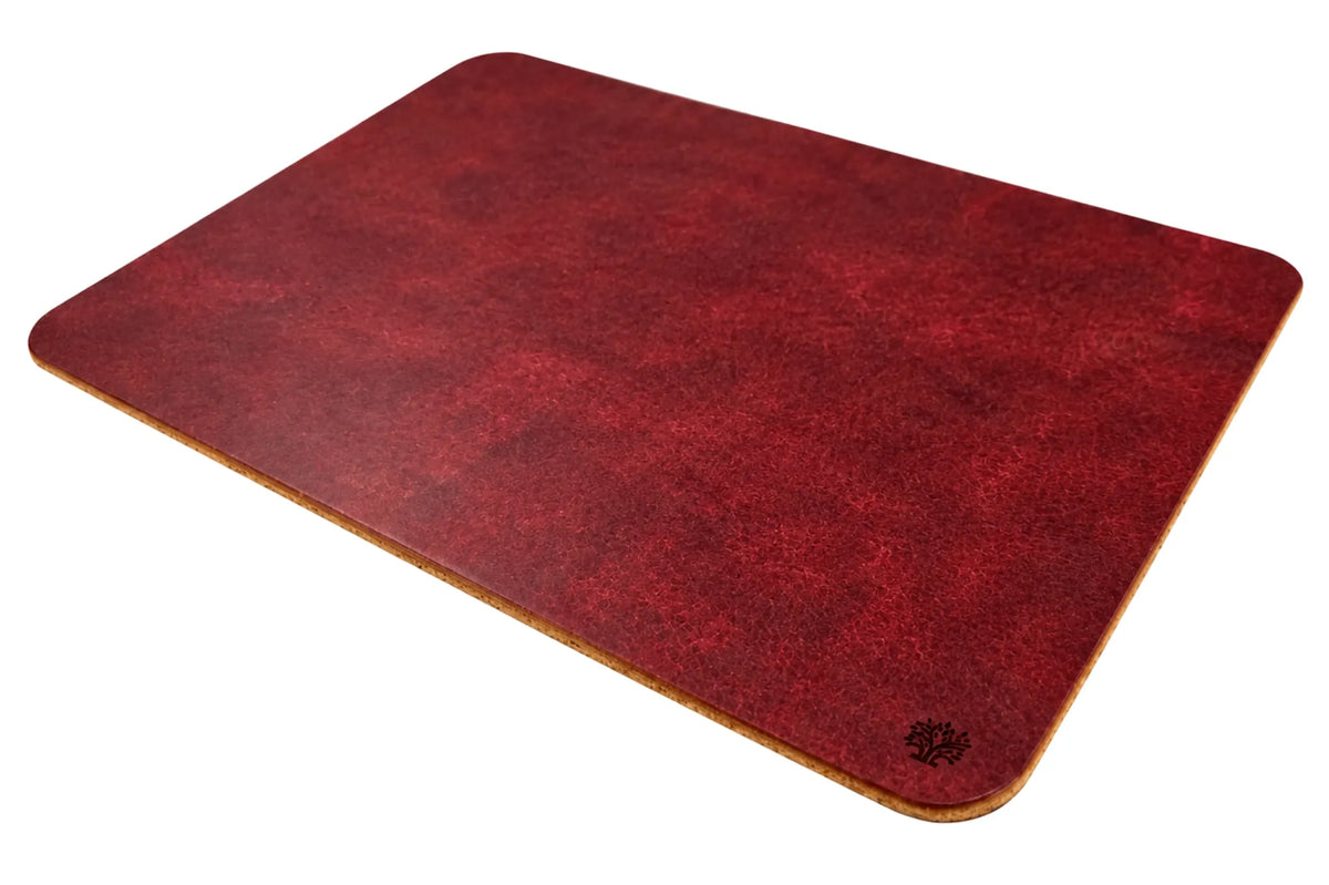 A Ridglea Rouge red, veg-tanned leather rectangular mouse pad with rounded corners, angled to highlight the cork bottom, featuring a small Lonoke Designs logo in the bottom-right corner, set against a plain white background.