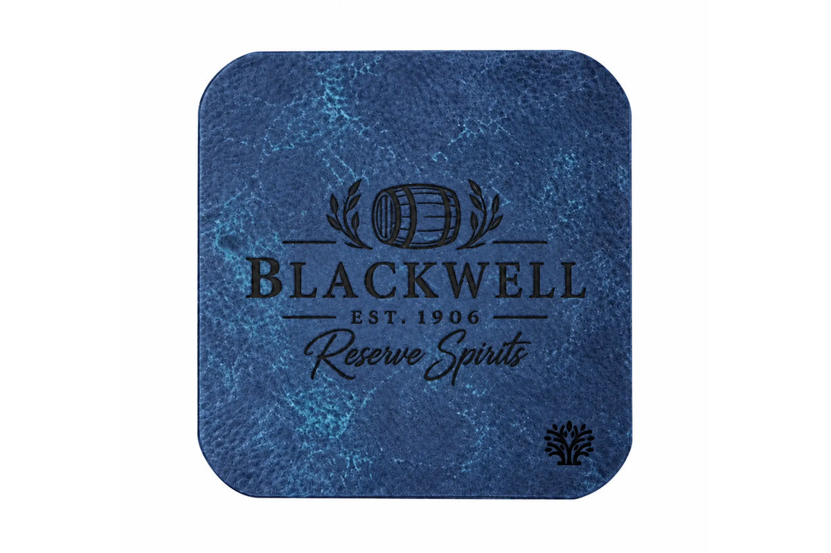 A Sapphire blue veg-tanned leather square coaster with rounded corners, featuring a small Lonoke Designs logo in the bottom right corner, set against a plain white background. Featuring an example of a company's custom laser engraving.