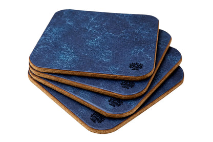 A stack of four square coasters with rounded corners, featuring a Sapphire blue vegetable-tanned leather top surface and a natural cork bottom, with a small Lonoke Designs logo printed on the corner.
