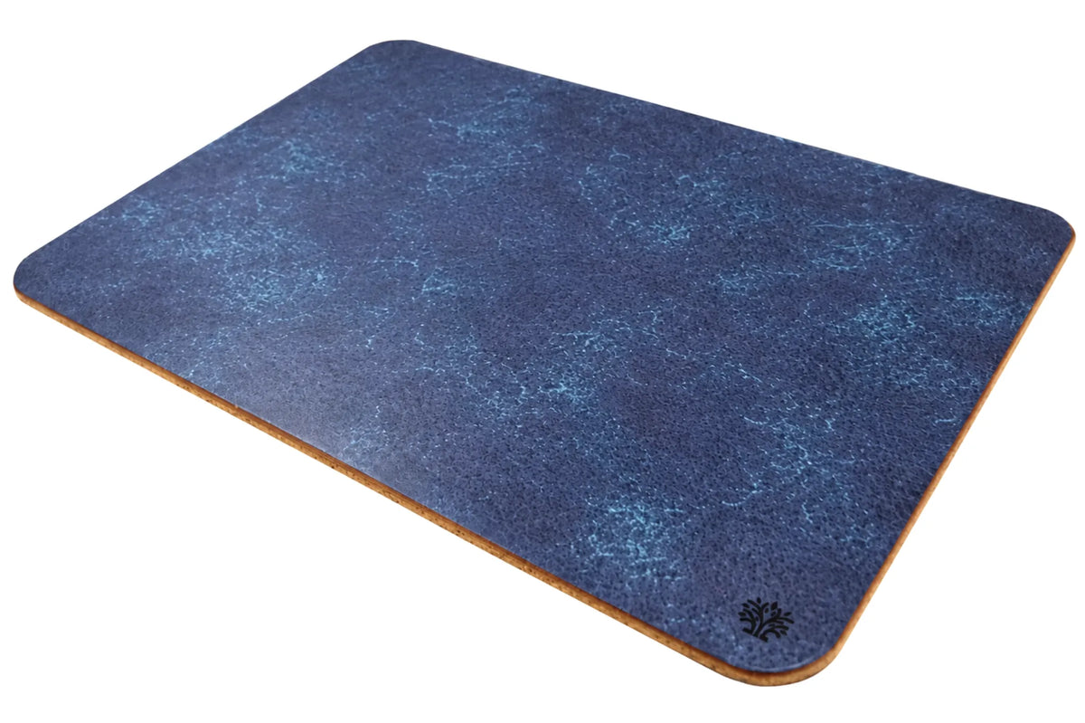A Sapphire blue, veg-tanned leather rectangular mouse pad with rounded corners, angled to highlight the cork bottom, featuring a small Lonoke Designs logo in the bottom-right corner, set against a plain white background.