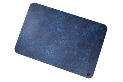 A Sapphire blue, veg-tanned leather rectangular mouse pad with rounded corners, angled to highlight the cork bottom, featuring a small Lonoke Designs logo in the bottom-right corner, set against a plain white background.