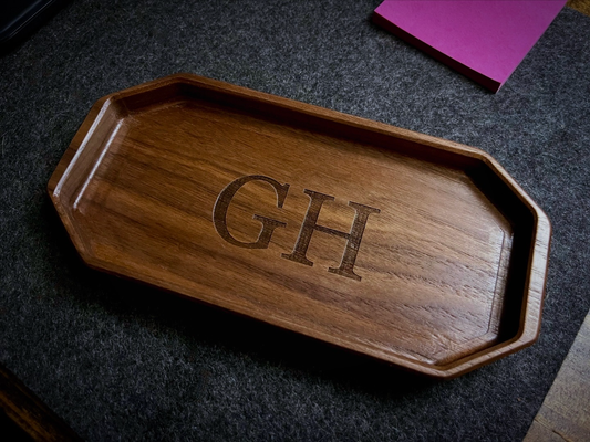 Wooden tray with engraved initials 'GH' on a dark wool felt desk pad by Lonoke Designs.