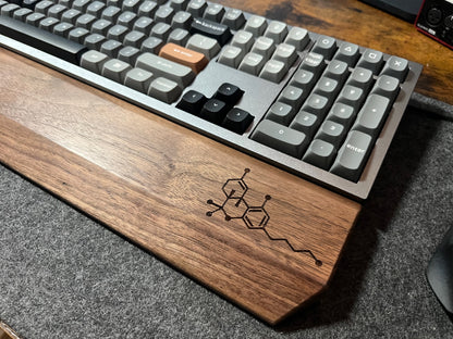 Mechanical keyboard with Walnut keyboard wrist rest, custom-engraved with a molecule. Sitting on a charcoal, wool felt and cork desk pad. Handcrafted and laser-engraved in-house at Lonoke Designs.