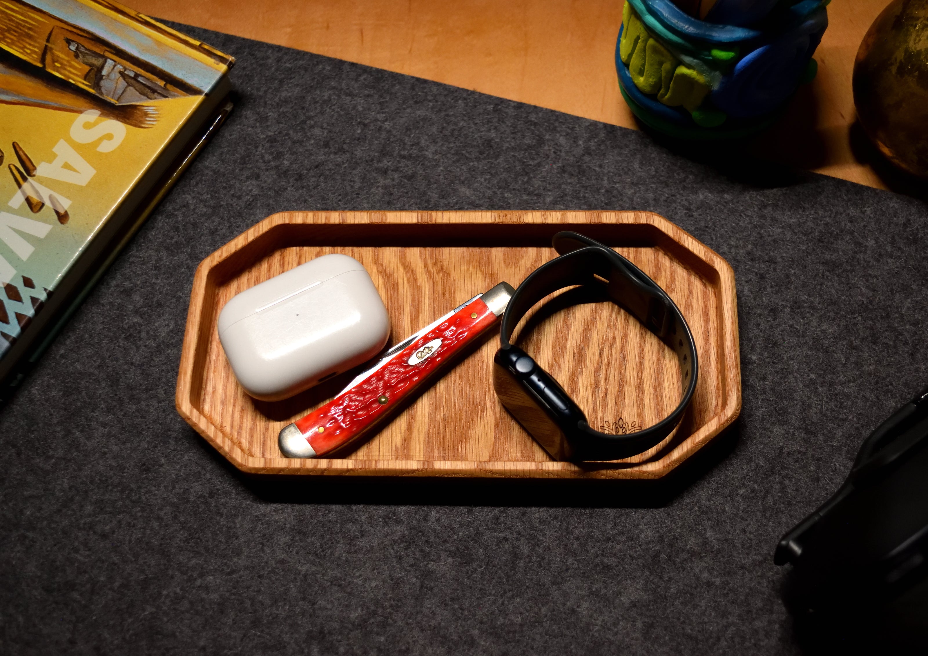 Oak EDC tray by Lonoke Designs holding a pocket knife, smartwatch, and AirPods on a wool desk pad, handcrafted in Texas.