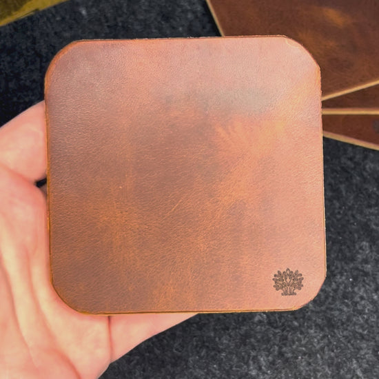 A video of the Lonoke Designs leather coasters being showcased on a charcoal wool felt and cork desk pad.