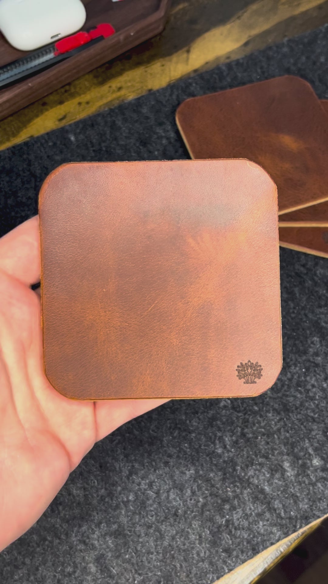 A video of the Lonoke Designs leather coasters being showcased on a charcoal wool felt and cork desk pad.