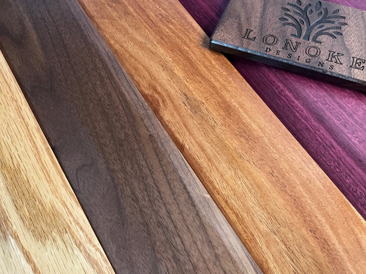Wooden samples with a walnut Lonoke Designs plaque on a purpleheart board.